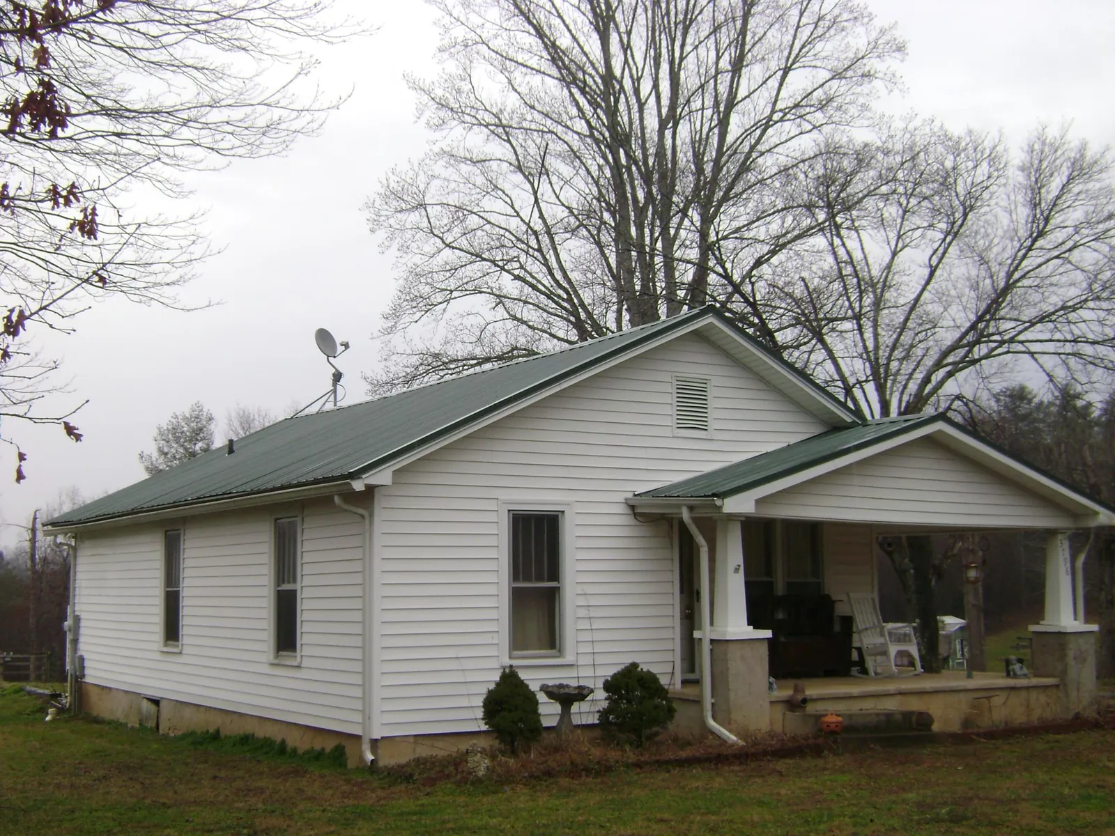 Green metal roof on a white bungalow with a side porch in Palmyra
