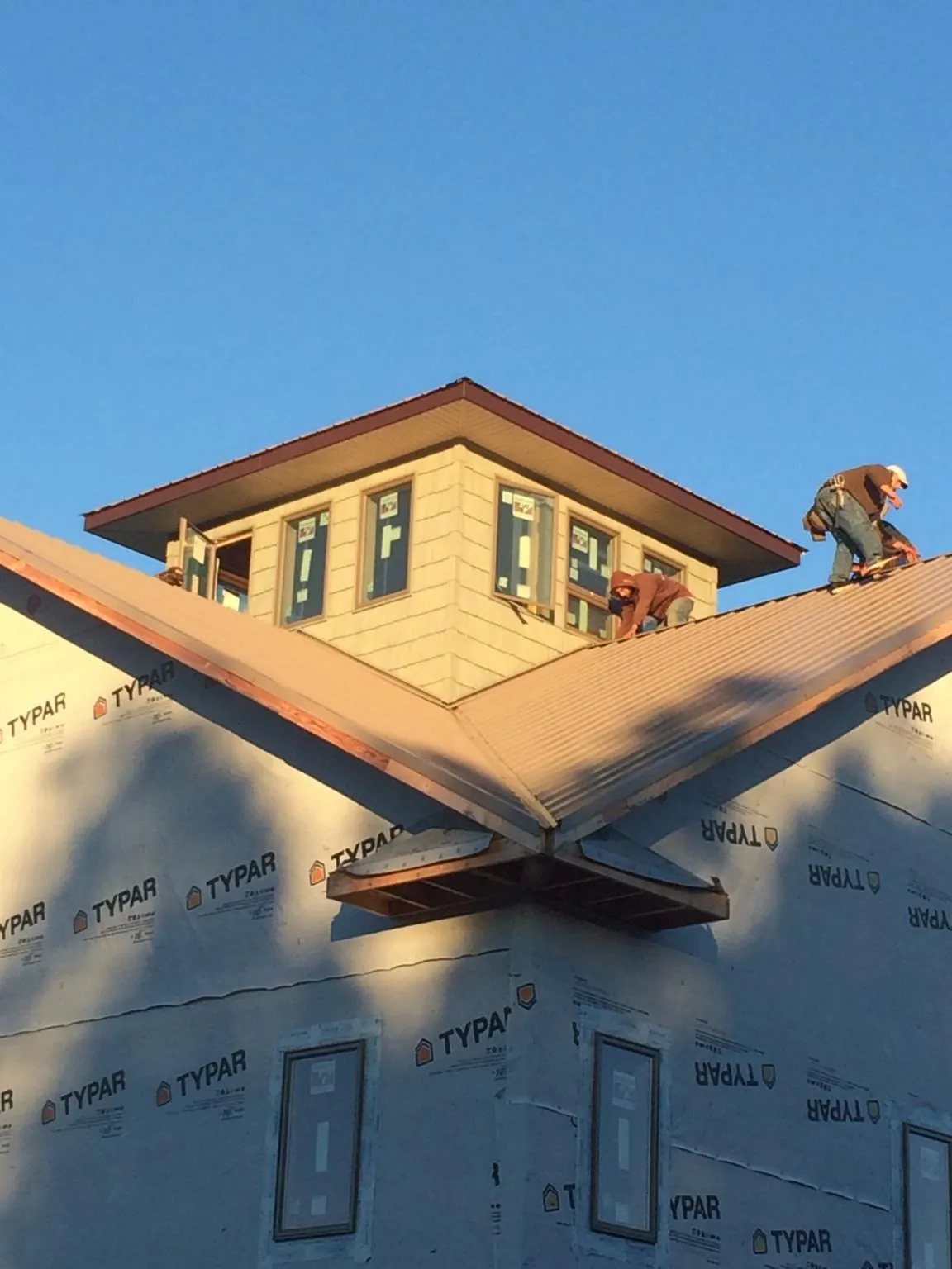 Roofers working around a rooftop cupola on a new metal roof at sunset — Roof Waterproofing in Palmyra by Roofing Brothers